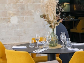 A dining table set with multiple wine glasses and a vase with dried flowers. - Mercure Rochefort La Corderie Royale (Rochefort)