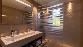 A modern bathroom with a large mirror, a white sink, and a shower area.