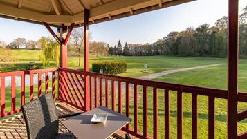 Un espacio al aire libre techado con una mesa y sillas, con vistas a un campo de golf.