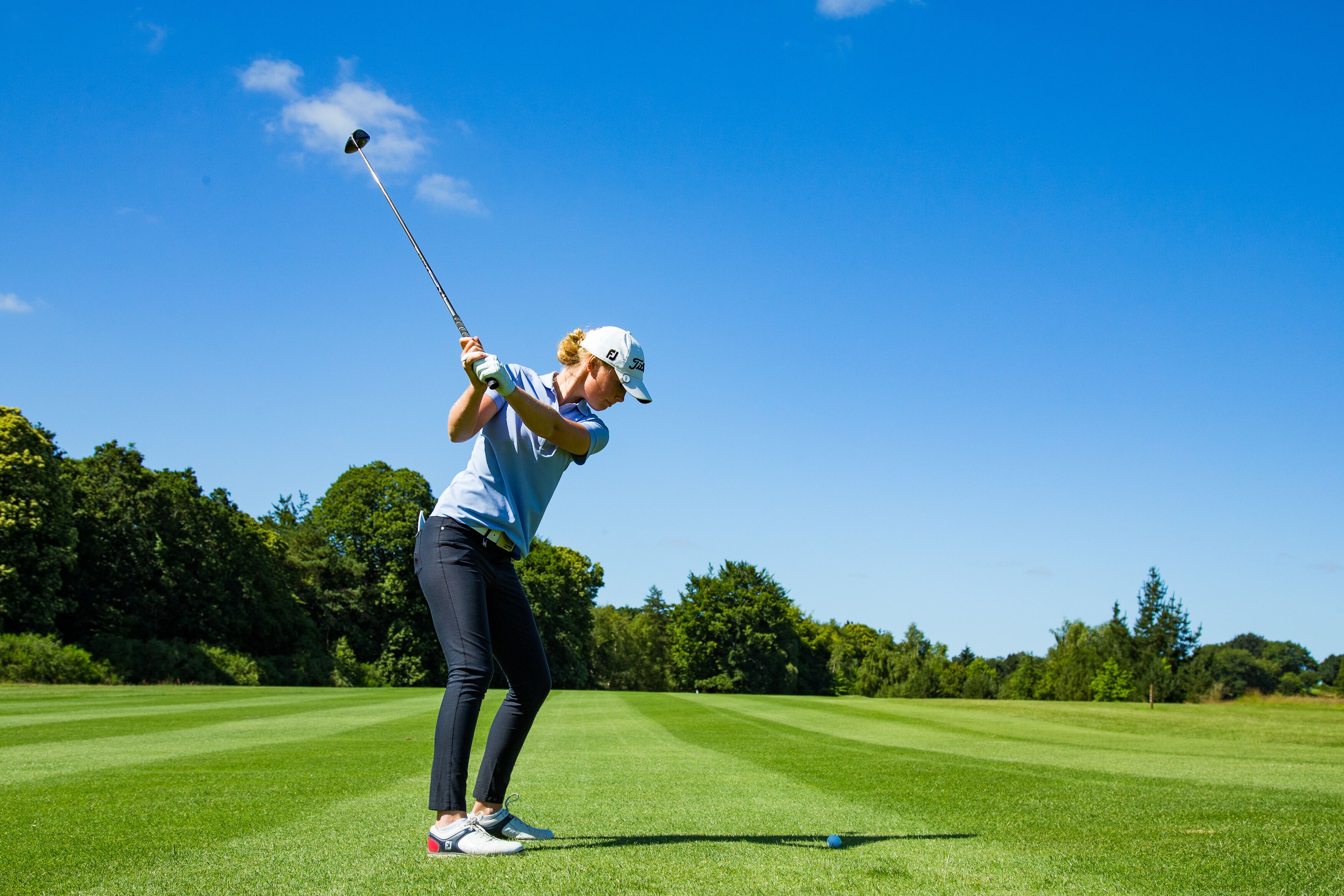 Una persona jugando al golf en un día soleado.