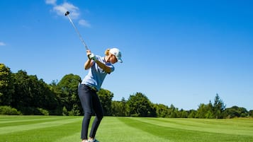 Una persona jugando al golf en un día soleado.