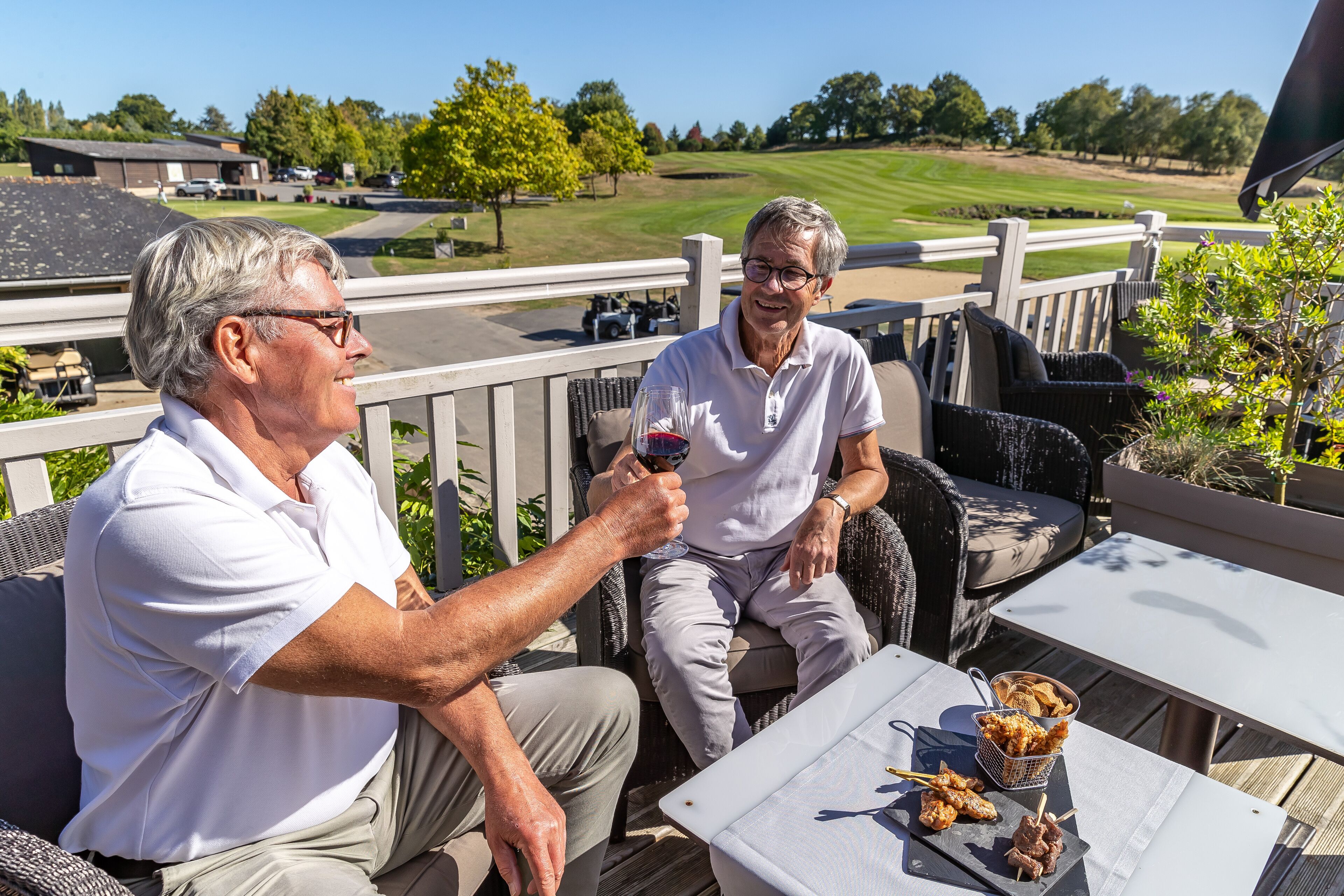 Two people seated at an outdoor table with a view of a golf course.