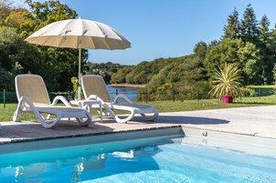 Una piscina al aire libre, sillones reclinables de piscina