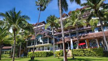A multi-story hotel with balconies, palm trees, and a clear blue sky.