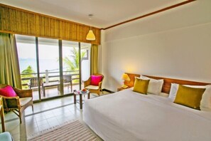 A hotel room with a large bed, a balcony with a view, and a small table with chairs.