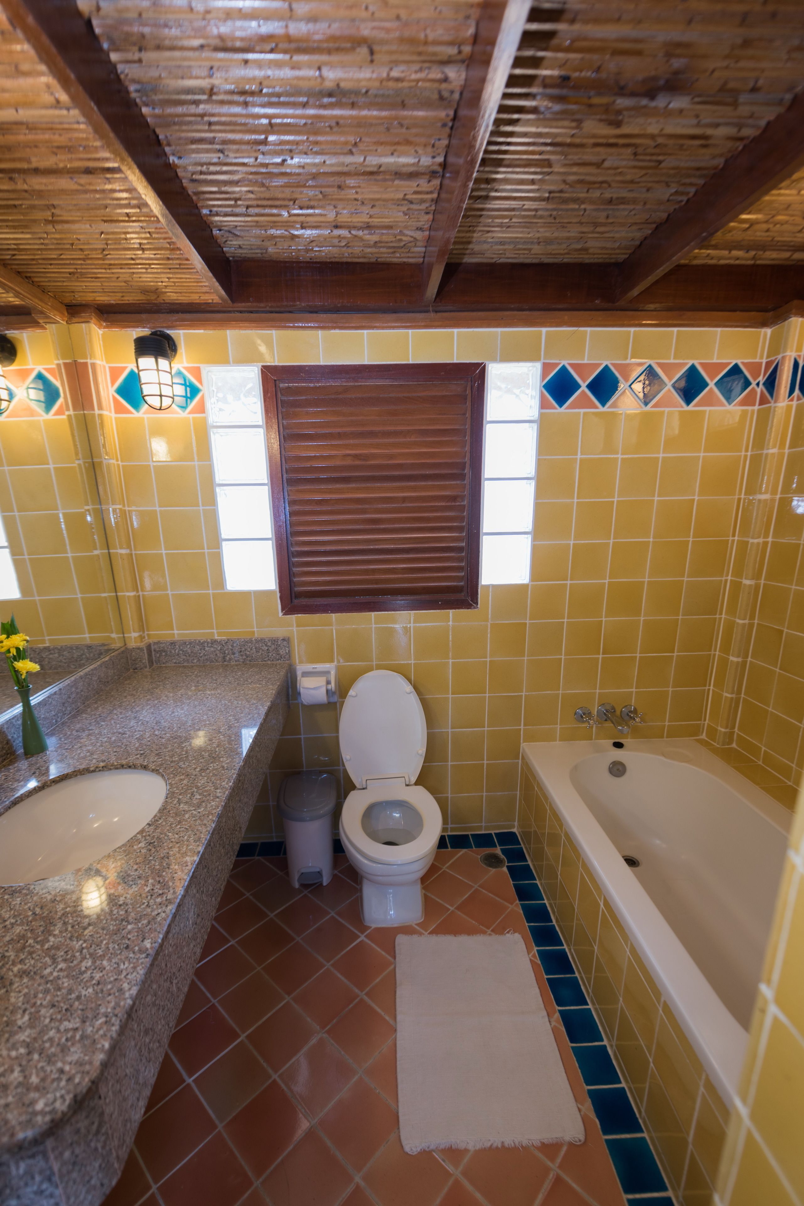 Un baño con techo de madera, lavabo, inodoro y bañera.