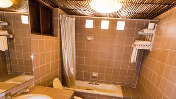 A bathroom with two sinks, a toilet, a bathtub, and a shower curtain.