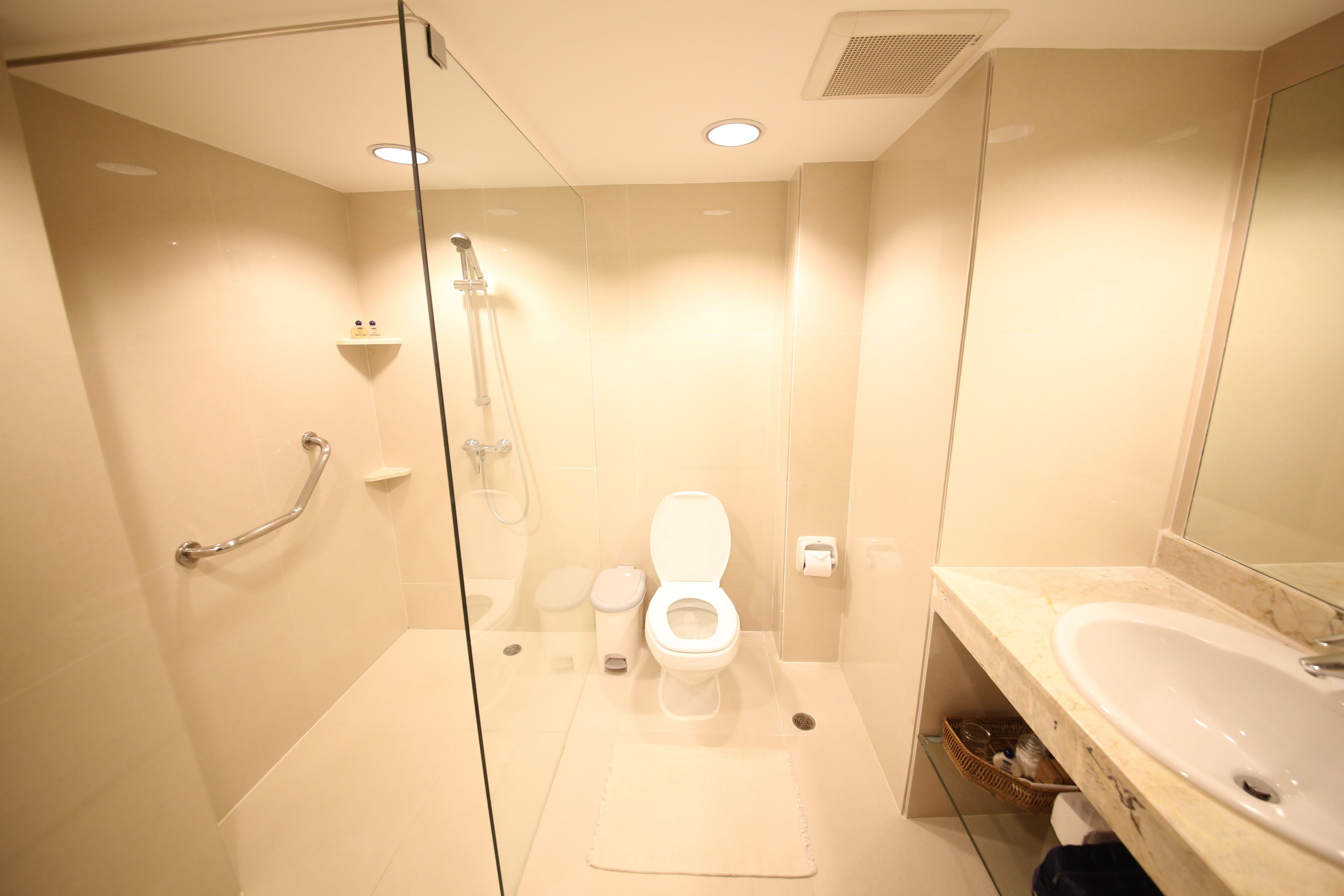 A modern bathroom with a glass shower enclosure, a white toilet, and a sink with a marble countertop.