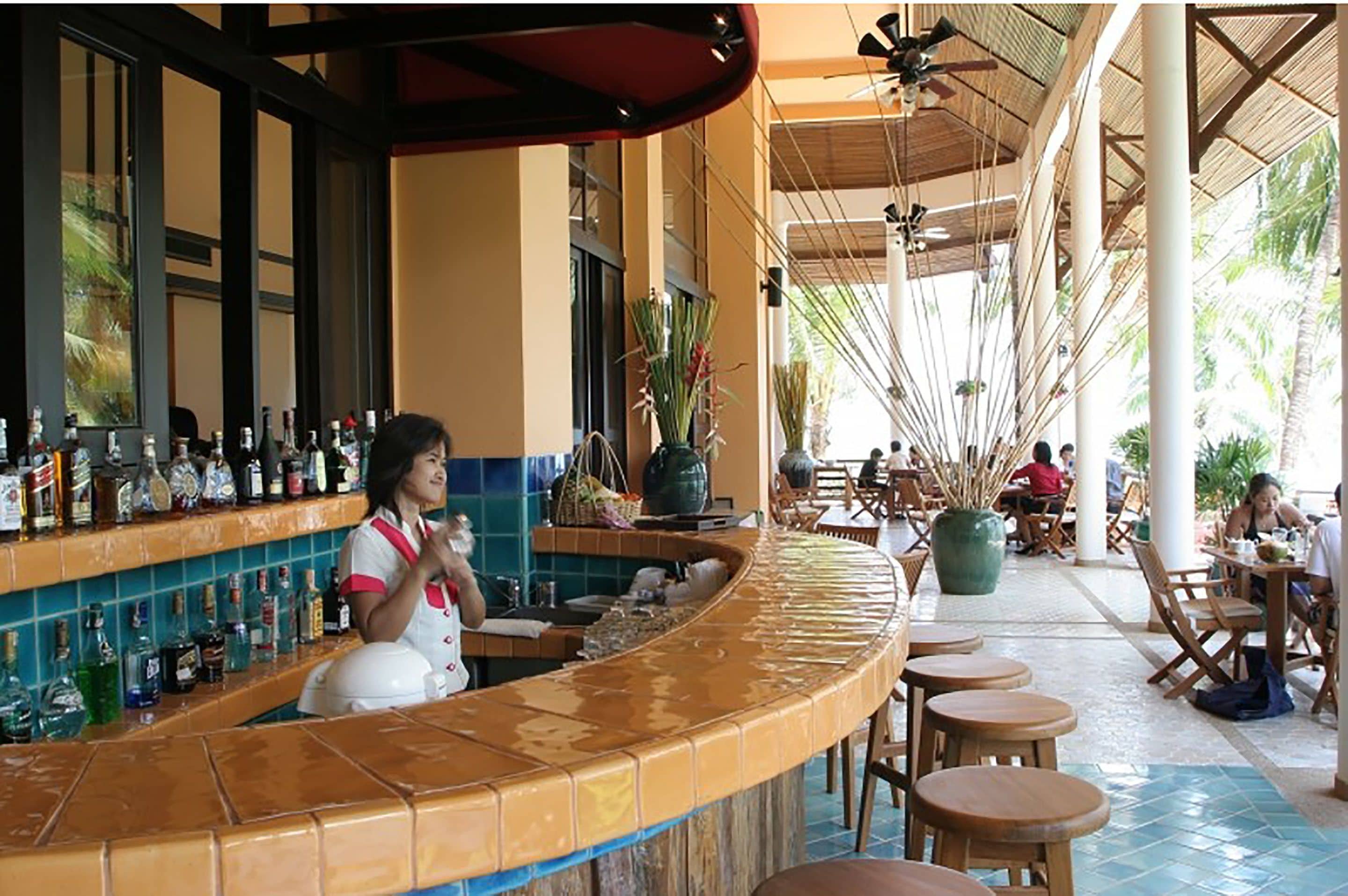 A bar area with a curved counter, multiple stools, and a seating area with tables and chairs.