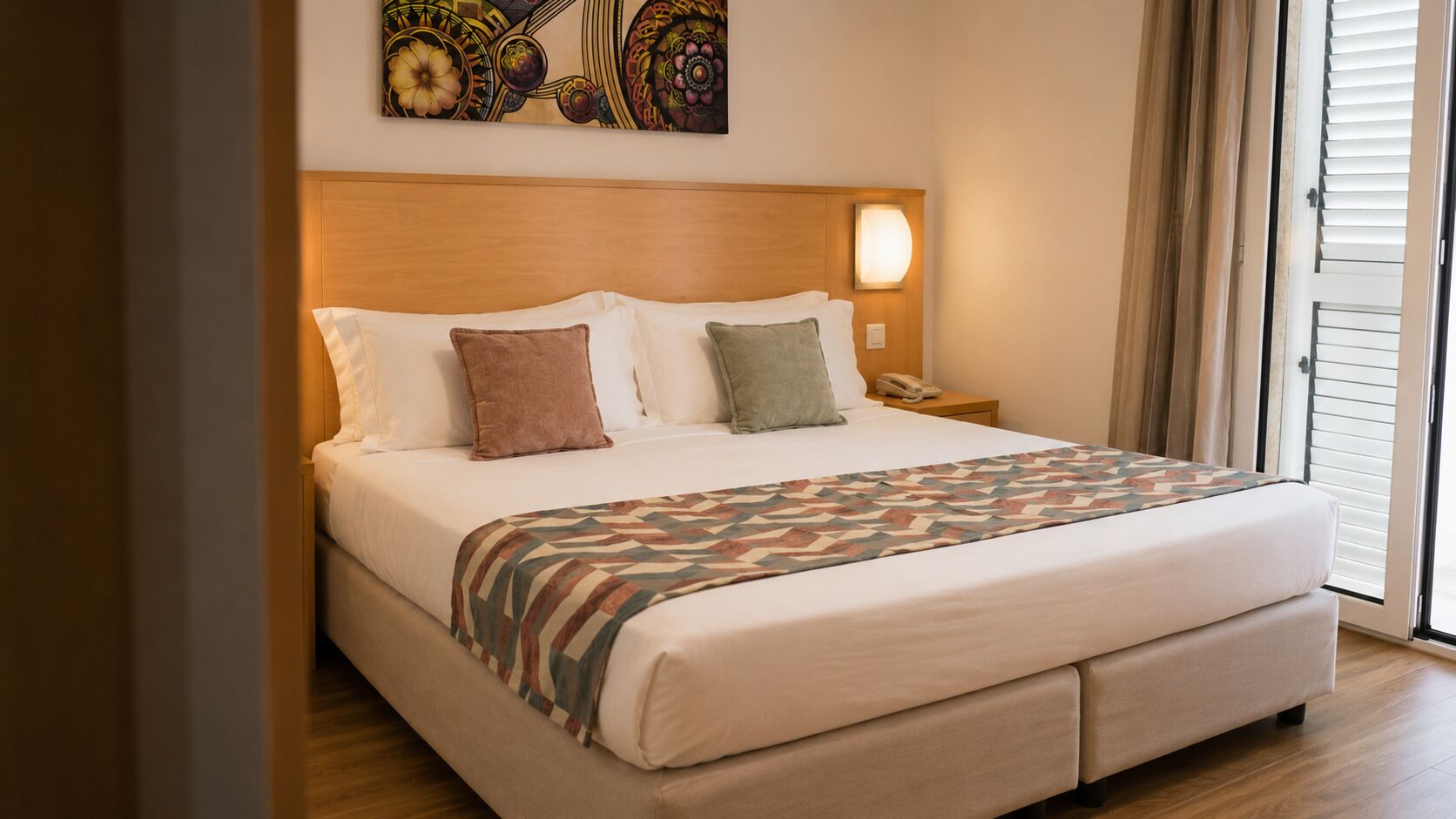 Una habitación de hotel con una cama, una mesita de noche, un teléfono y una ventana con cortinas.