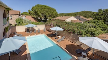 Relax by the serene pool surrounded by lush greenery and a picturesque view.