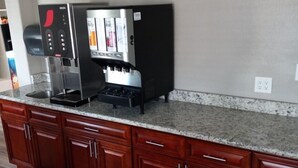 A kitchen with a built-in coffee machine, wooden cabinets, and a granite countertop. - Travelodge by Wyndham San Antonio Downtown Northeast (San Antonio)