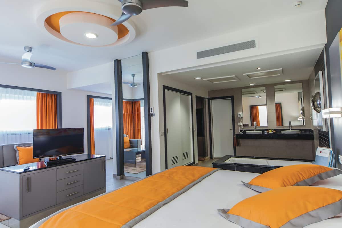 A hotel room with a bed, a TV, a desk, and a bathroom.