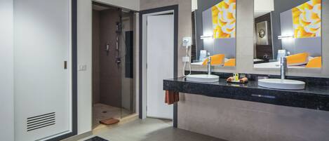 A modern bathroom with a large mirror, two sinks, a shower, and a bathtub.