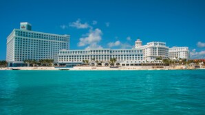 A large resort hotel with multiple buildings, a beach, and a clear blue sky. - Hotel Riu Cancun -  Adults Only - All Inclusive (Cancun)