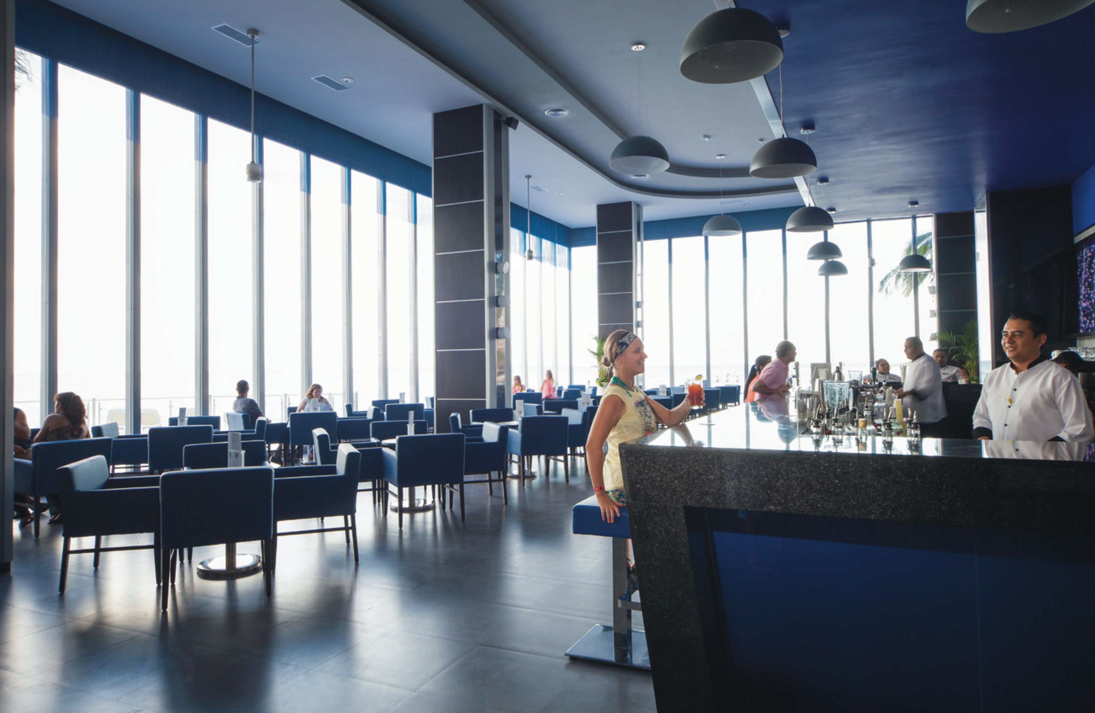 A spacious restaurant with high ceilings, large windows, and modern lighting fixtures.