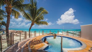 A hot tub area with a view of the beach and ocean, surrounded by palm trees and a fence. - Hotel Riu Cancun -  Adults Only - All Inclusive (Cancun)