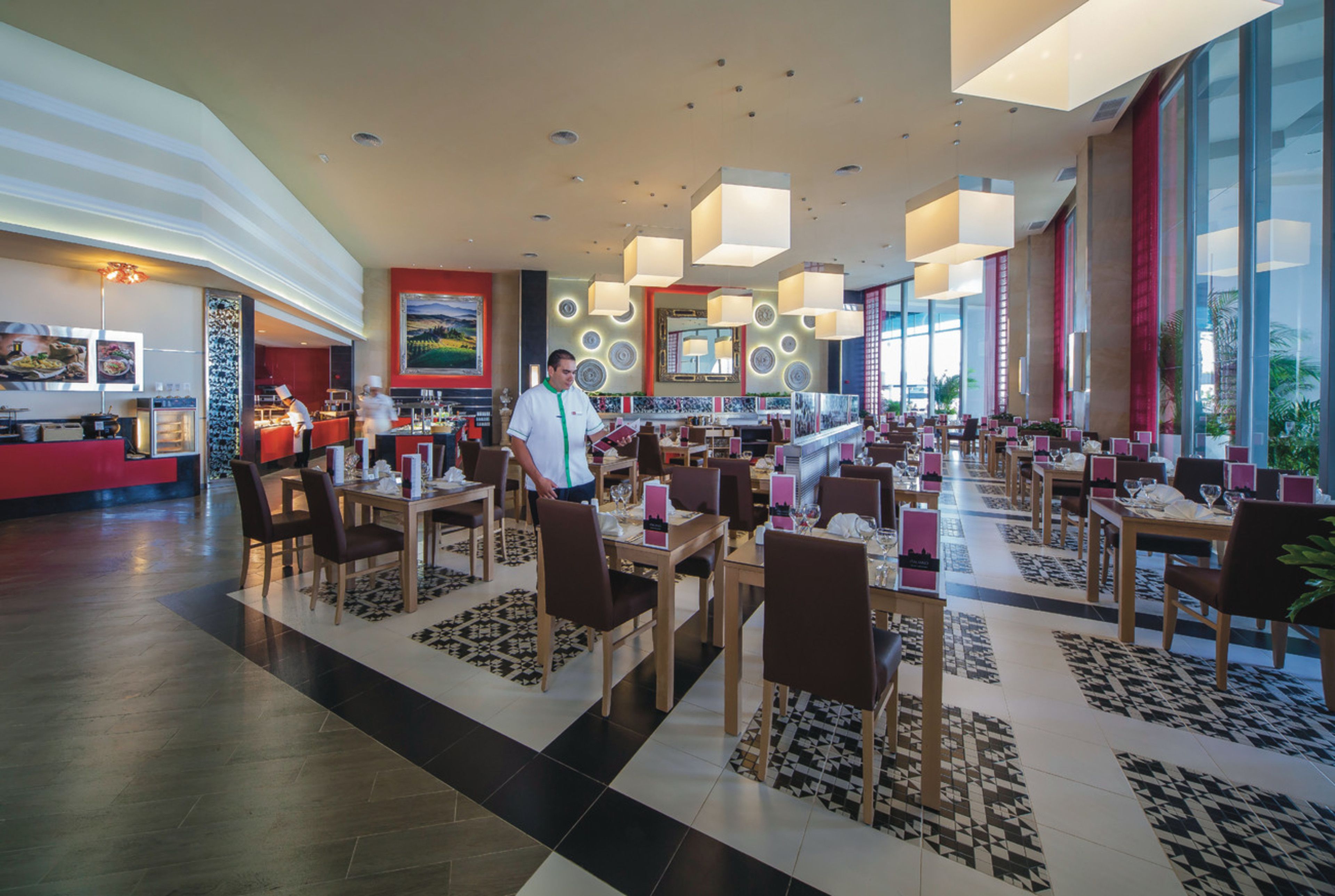 Un amplio vestíbulo de hotel con varias zonas de restauración, una recepción y grandes ventanales que ofrecen vistas.