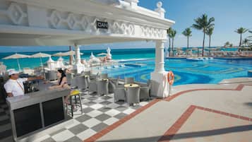 A poolside bar area with a checkered floor, white bar counter, and outdoor seating.
