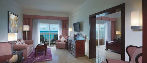 A hotel room with a living area, a dining area with a view, a large mirror, and a television.