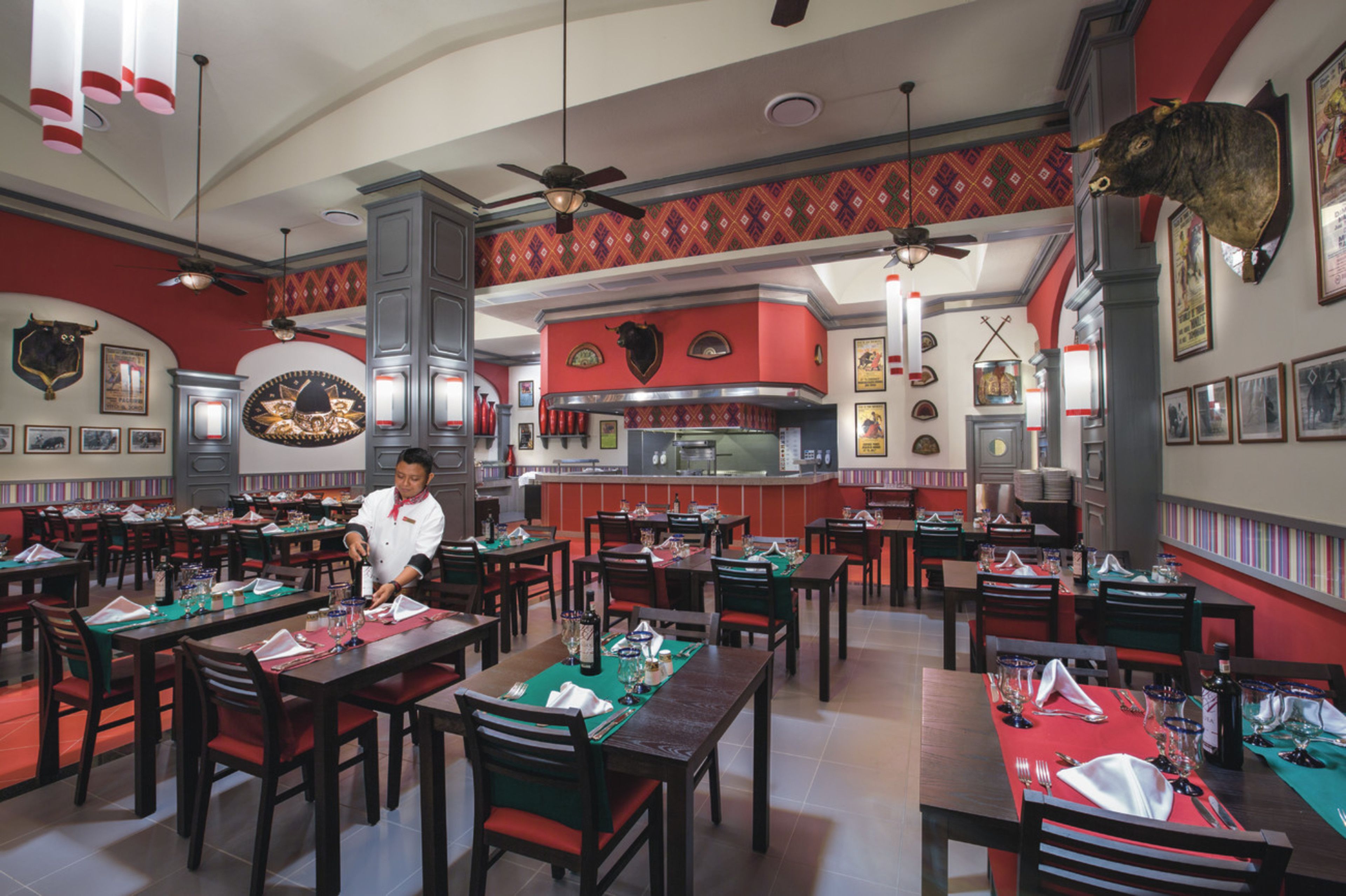 Un restaurante con varias mesas, sillas y un chef preparando comida.