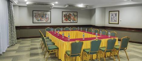 A conference room with a long table, green chairs, and water bottles.