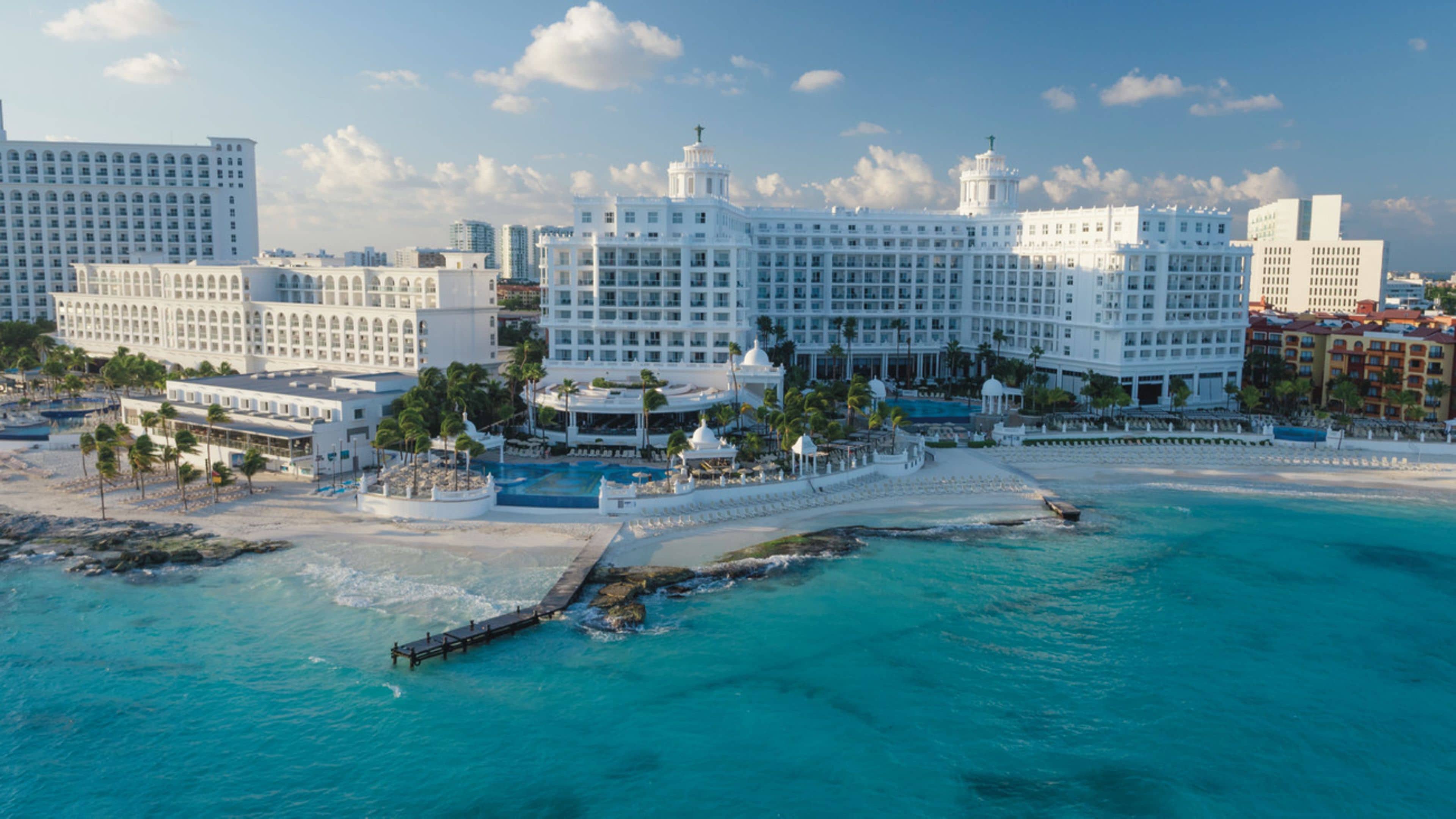 A large resort with multiple buildings, a beach, and a pier.