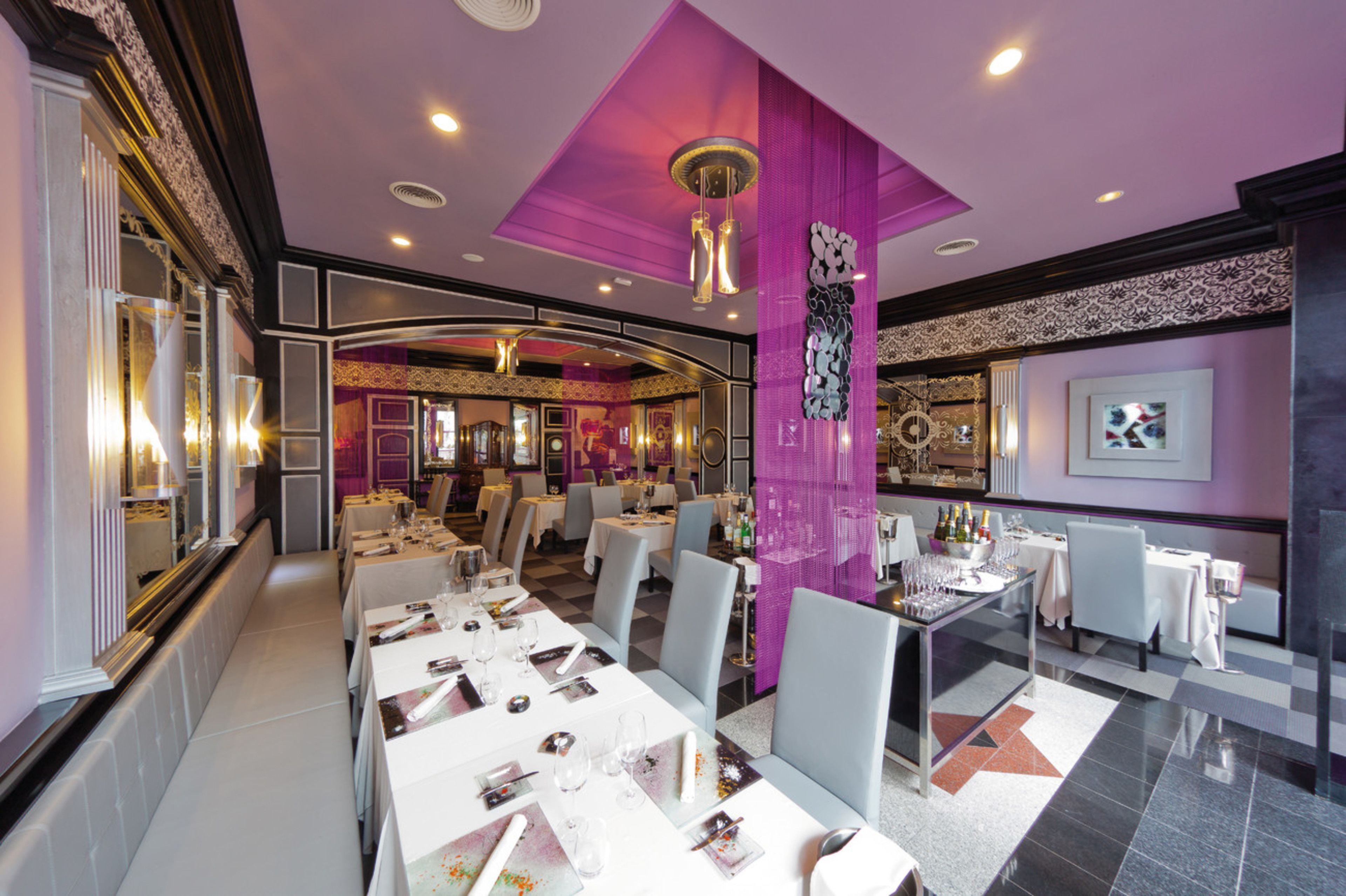 A modern restaurant with white tables and chairs, purple accents, and a checkered floor.