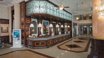 A lobby with a reception desk, a digital kiosk, and a chandelier.