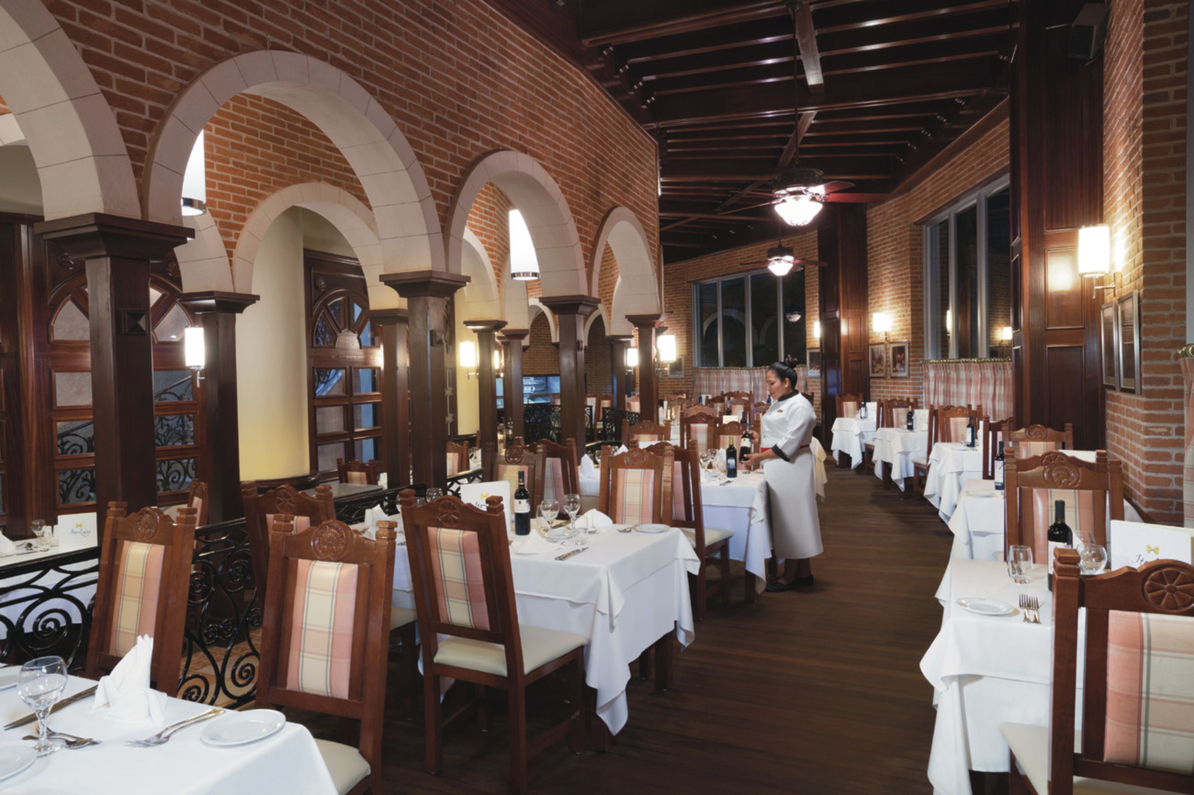 A restaurant with brick walls, arched ceilings, and white tablecloths.