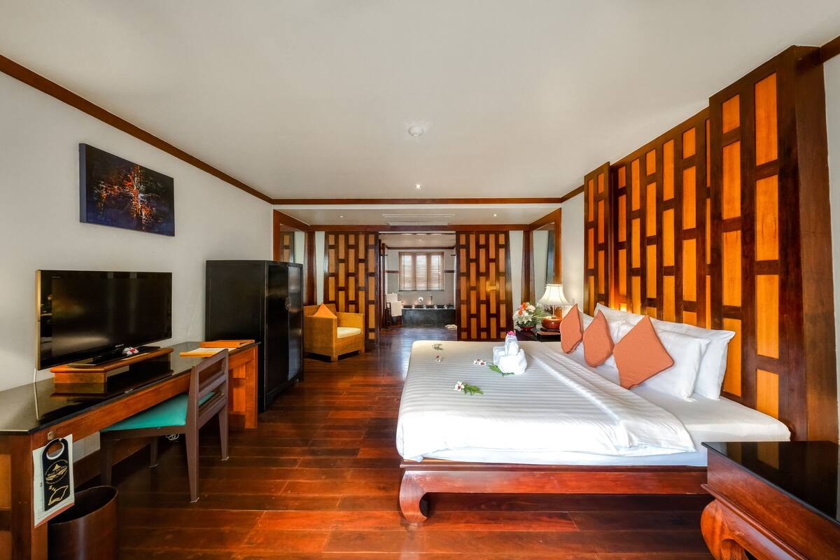 Habitación de hotel con cama, televisión, escritorio y vista al comedor.