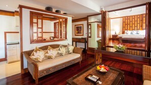 Habitación de hotel con sofá, una mesita de centro con fruta, un espejo y una cama con almohadas.