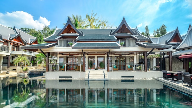 Un resort con una amplia piscina, arquitectura tradicional y un paseo techado.