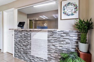 A reception area with a tiled counter, a digital kiosk, and a framed artwork on the wall.