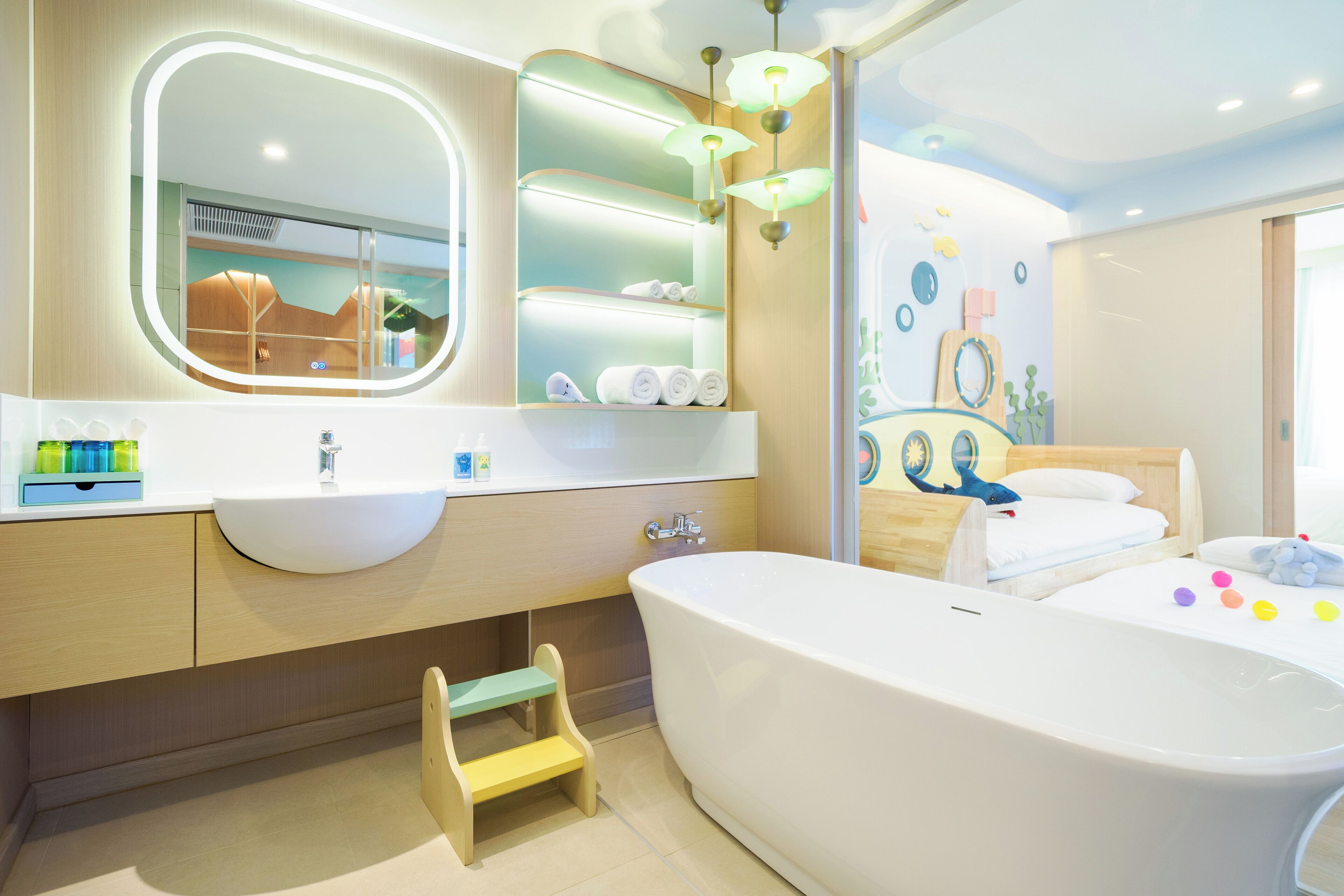 A modern bathroom with a large bathtub, a vanity with a mirror, and a step stool.
