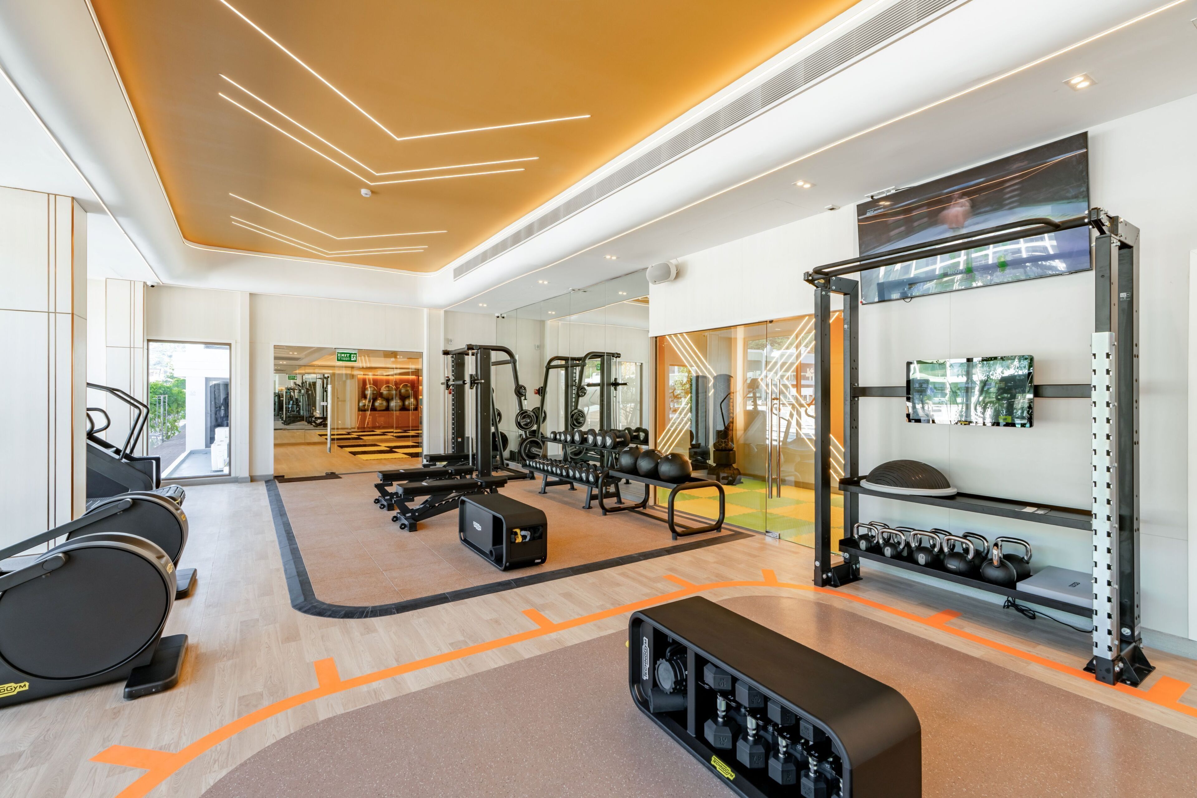 Un gimnasio moderno con cintas de correr, máquinas de pesas y pesas libres.