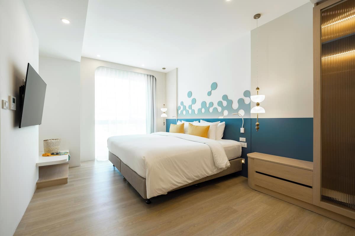 Ein modernes Hotelzimmer mit Bett, Nachttisch und Fernseher.