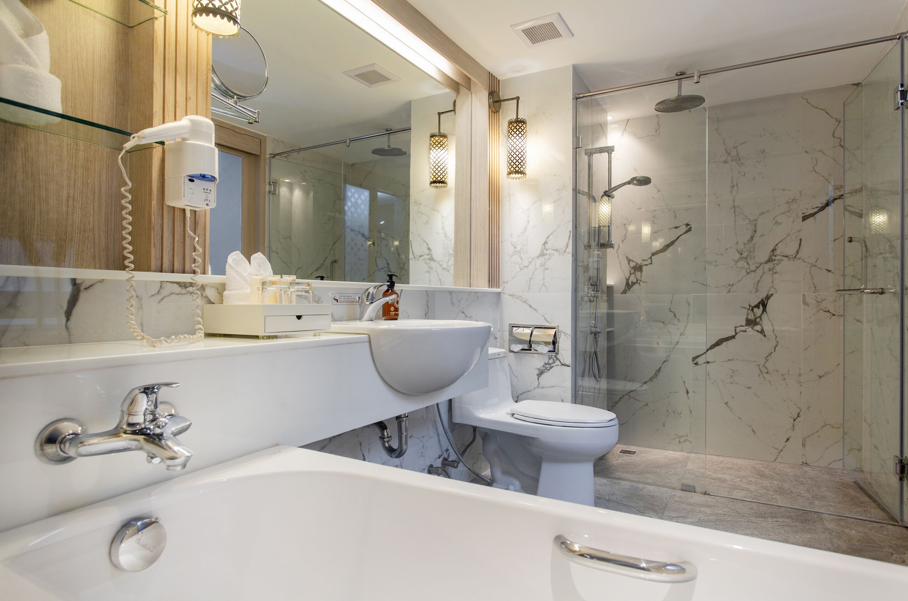 A modern bathroom with a bathtub, a sink, a toilet, and a glass-enclosed shower area.