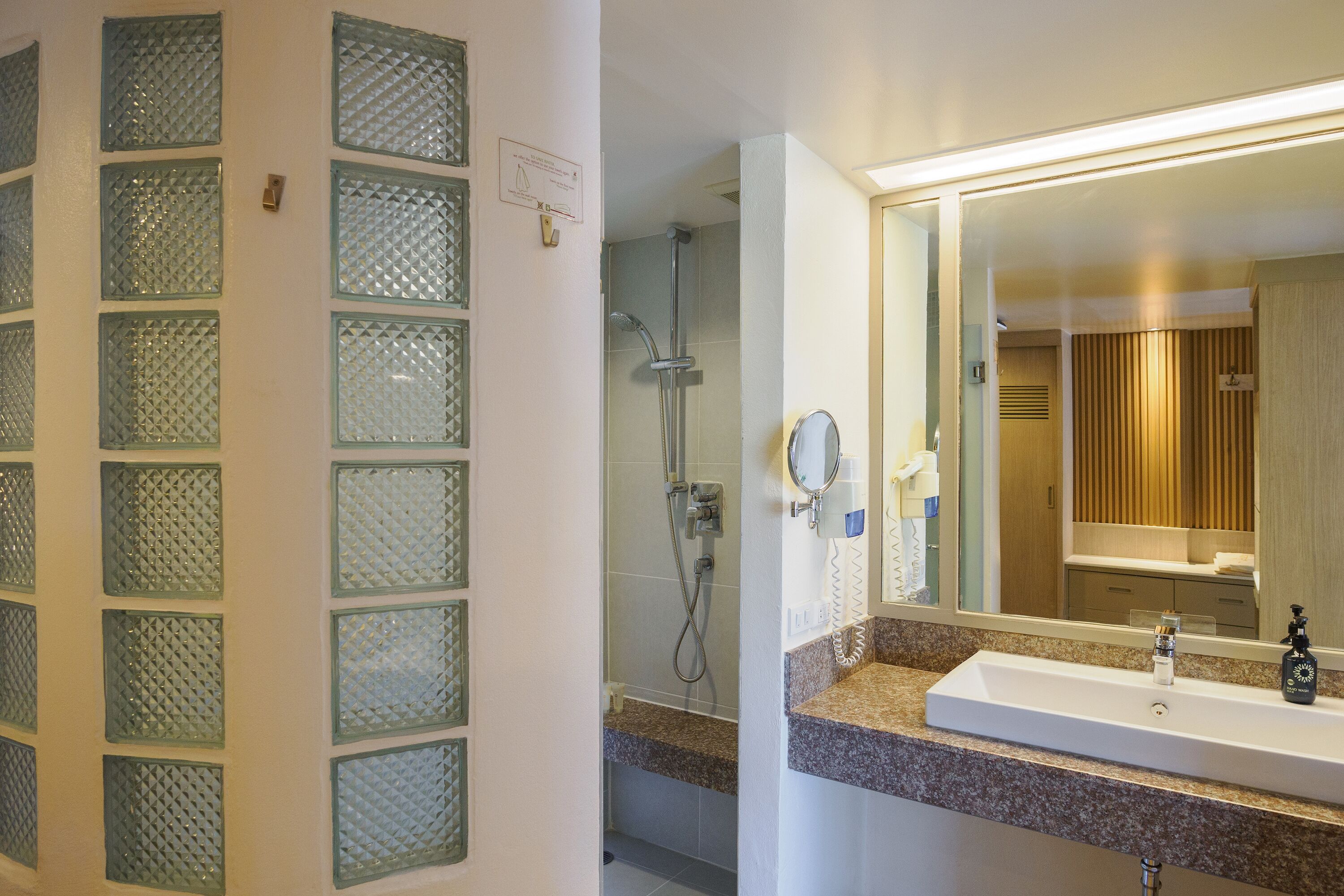 A bathroom with a glass shower enclosure, a sink with a mirror, and a towel rack.