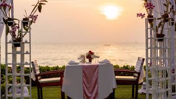 An outdoor dining setup with a table set for two, overlooking a body of water.