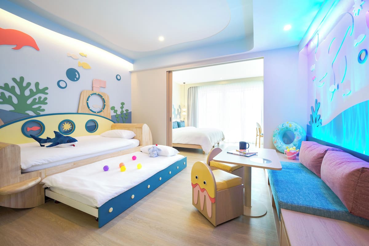Ein Kinderzimmer mit Etagenbetten, einem Spielbereich und einer Couch.