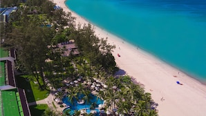 A beach resort with a swimming pool surrounded by palm trees, a sandy beach, and a view of the ocean. - Katathani Phuket Beach Resort (Karon)