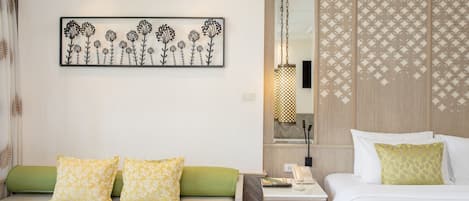 A hotel room with a bed, a sofa, a nightstand, a lamp, and a decorative wall piece.