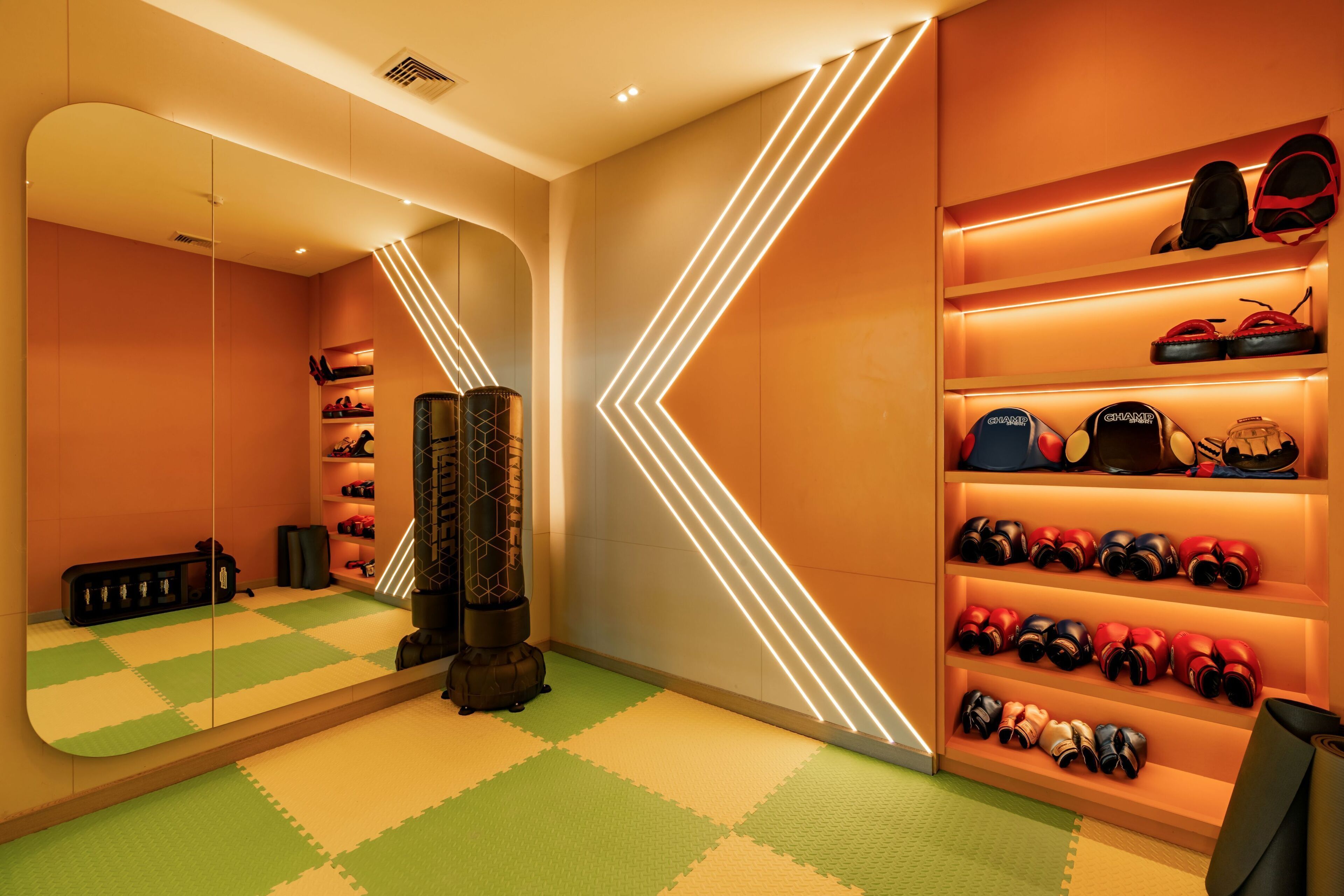 Une pièce avec un mur recouvert de miroirs, un sac de frappe et des étagères remplies de chaussures.