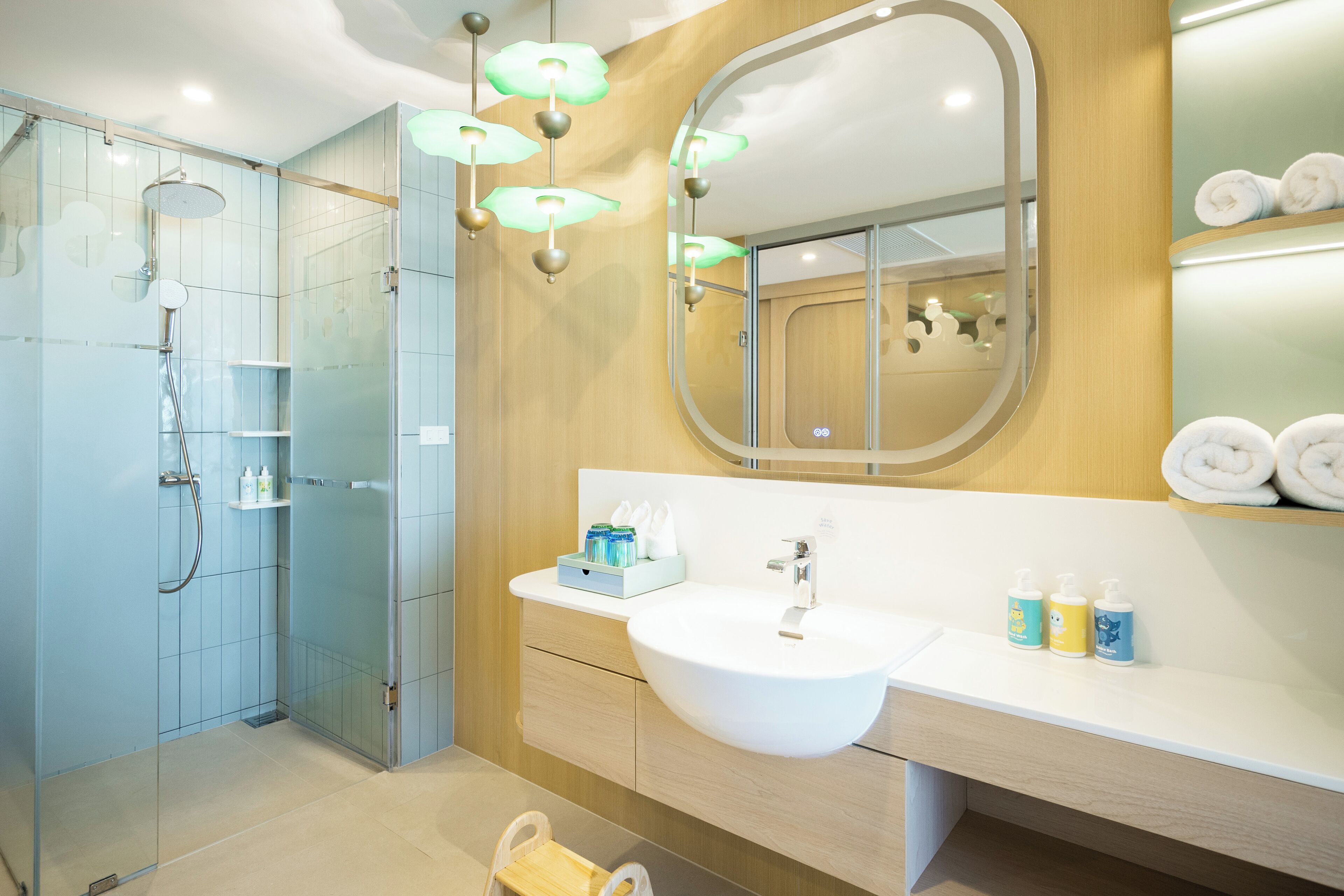 Un baño moderno con cabina de ducha de vidrio, un lavamanos blanco y un mueble de tocador de madera.