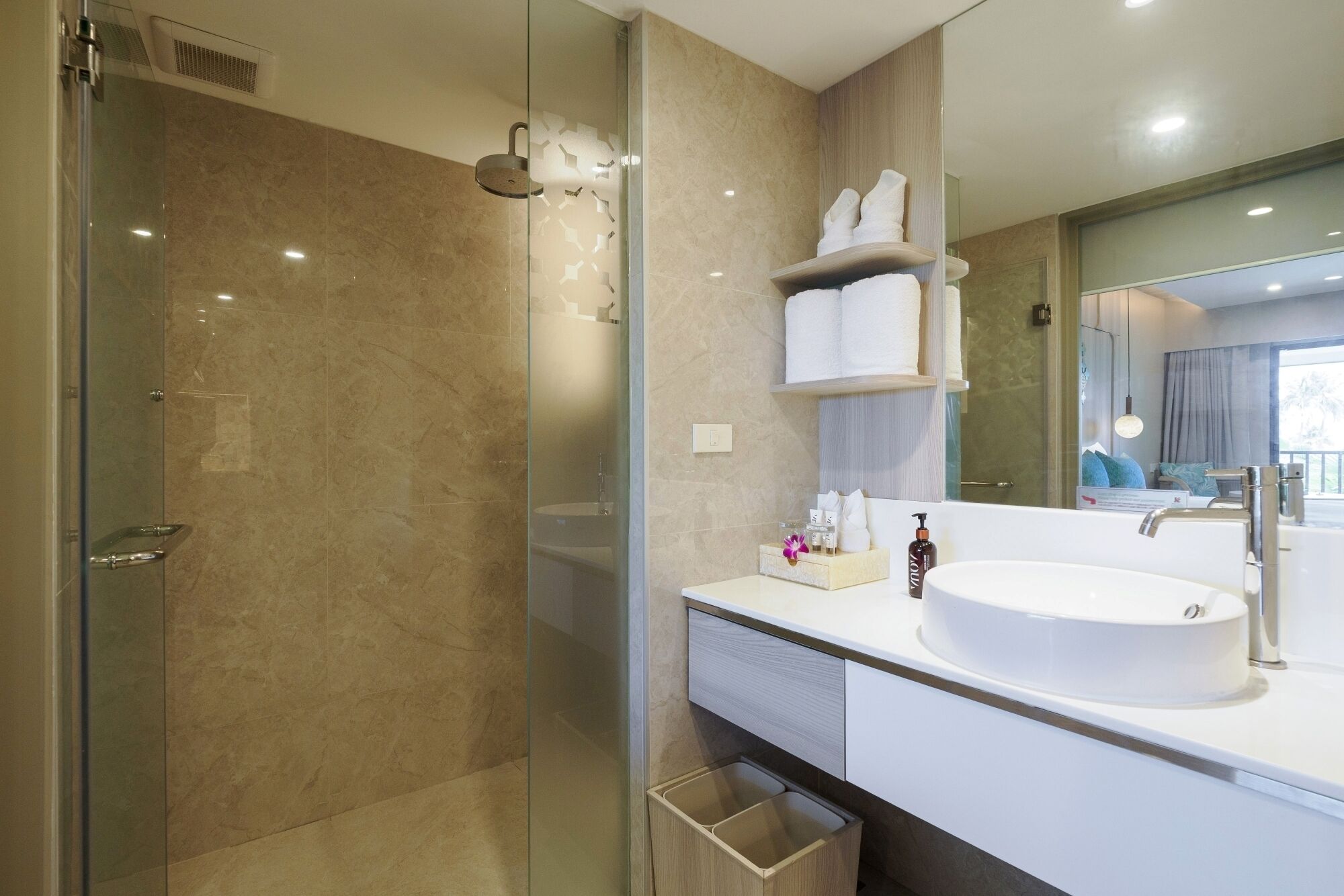 A modern bathroom with a glass-enclosed shower, a white sink, and a vanity with a mirror.