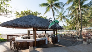 A beachside bar with a thatched roof, wooden deck, and outdoor seating. - Katathani Phuket Beach Resort (Karon)