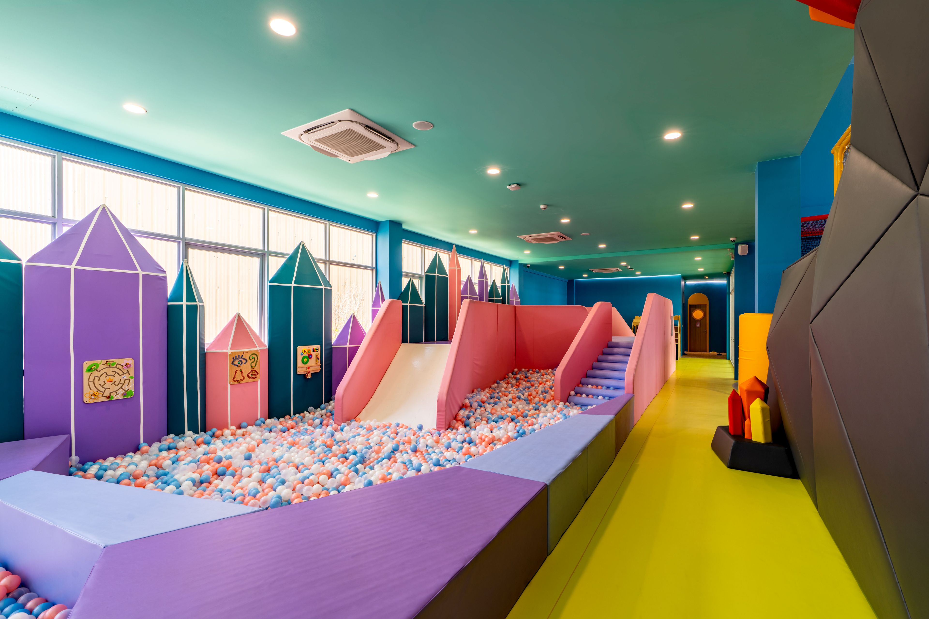 Zona infantil con piscina de pelotas, toboganes y estructuras de juego acolchadas.