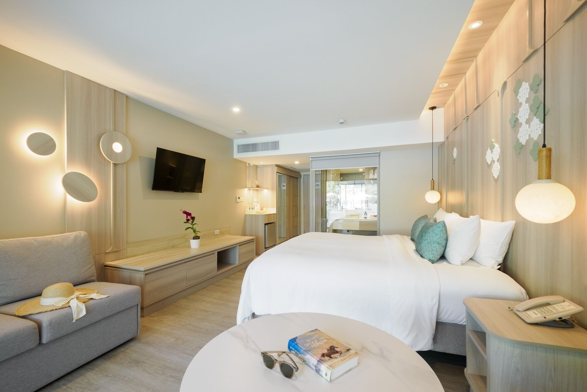 A modern hotel room with a large bed, a sofa, a desk, and a TV.