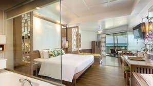 A modern hotel room with a large bed, a separate seating area, a view of the ocean, and a television. - Katathani Phuket Beach Resort (Karon)